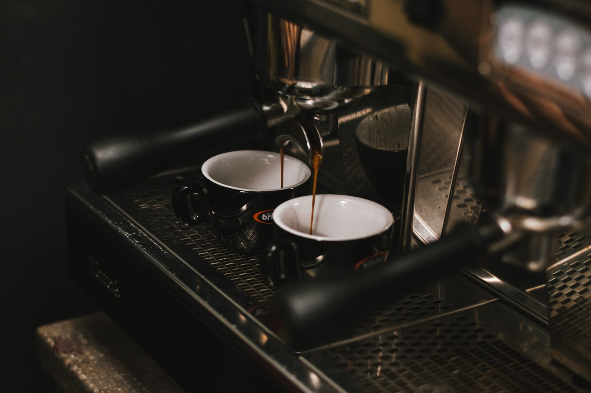 Coffee maker pouring coffee into two cups.